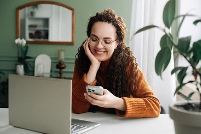 Young woman using mobile phone at home