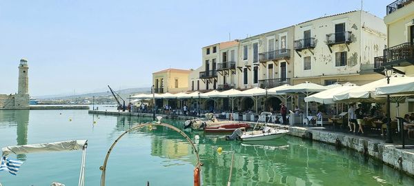 Boats moored in river with buildings in background