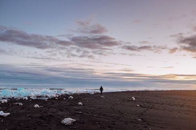 Woman on beach against sky during sunset