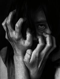 Close-up of depressed woman over black background