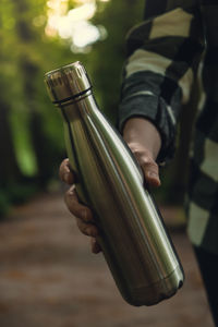 Close-up of unrecognizable female hand holding water bottle. reusable steel thermo water bottle in