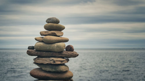 Stack of stones in sea against sky