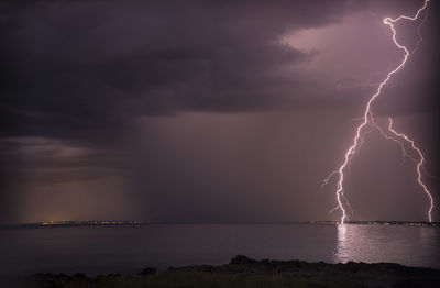 Lightning over sea against dramatic sky