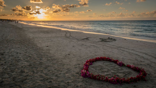 Heart shape on beach against sky during sunset