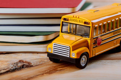 Close-up of yellow toy bus against stack of books on table