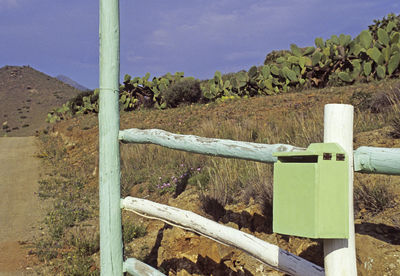 Close-up of wooden post on landscape against sky