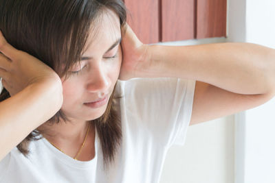 Close-up of young woman covering ears with hands