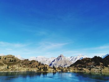 Scenic view of snowcapped mountains against blue sky