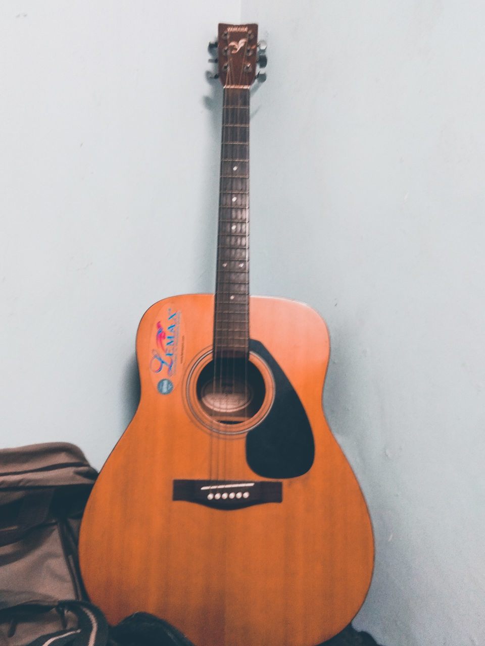 CLOSE-UP OF GUITAR AGAINST WHITE WALL