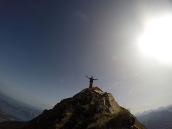 Low angle view of silhouette man standing on mountain against sky