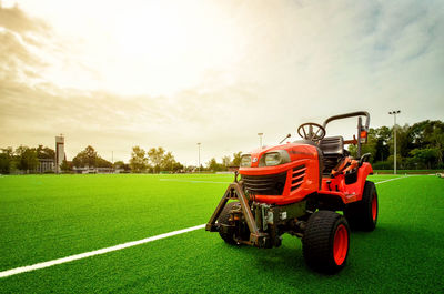 Tractor on field against sky during sunset