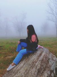 Woman sitting on a field, in a foggy forest