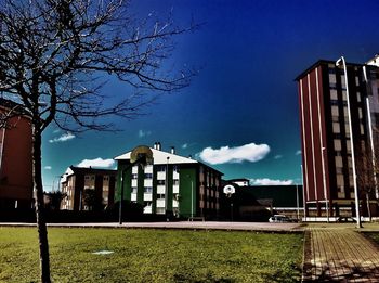 Houses and trees on field against blue sky