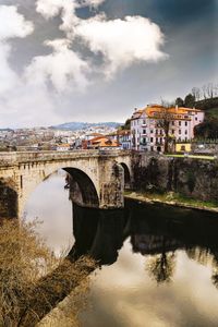 Bridge over river in city against sky