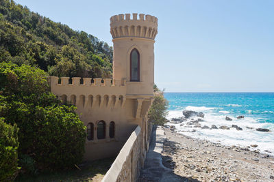 Castle near beautiful azure sea and the rocky beach, tyrrhenian sea in tuscany, italy