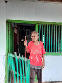 Full length of smiling woman standing against wall