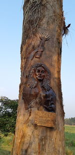 Low angle view of sculpture against tree trunk