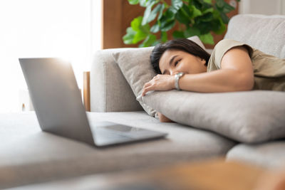 Smiling young woman lying on sofa at home