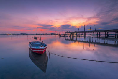 Boat moored in marina against sky during sunset