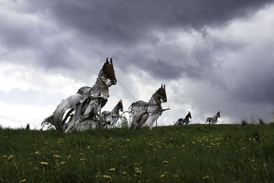 Statues ig horses on field against sky