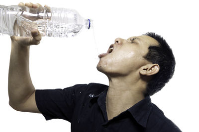 Mid adult man drinking water over white background