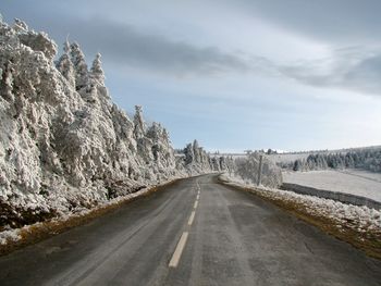 Road by snow covered trees against sky