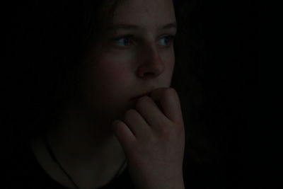 Close-up of beautiful young woman over black background