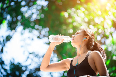 Sporty young woman drinking water outdoors