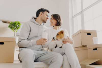 Low angle view of romantic couple with dog sitting in new house