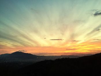 Scenic view of silhouette mountains against orange sky