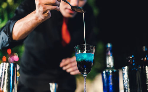 Midsection of man pouring wine in glass