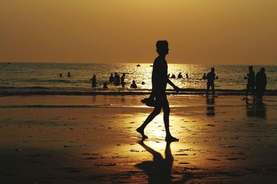 Silhouette people on beach against sky during sunset