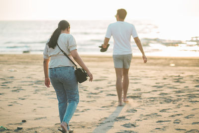 Rear view of couple standing at beach