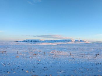 Scenic view of snow covered land against blue sky