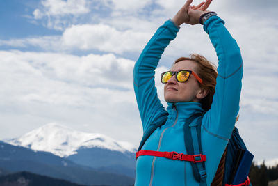 Low angle view of young woman standing against mountain