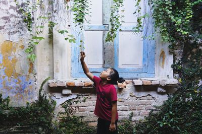 Girl holding plants by house