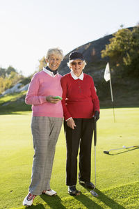 Full length portrait of senior female golfers standing on golf course