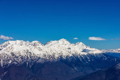 Scenic view of snowcapped mountains against blue sky