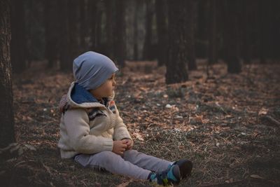 Cute boy sitting on field in forest