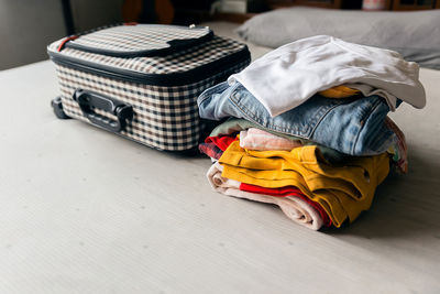 Pile of belongings, colorful of clothes and luggage on the bed.