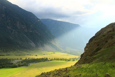 A ray of light in a high-altitude green valley with huge mountains