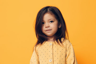 Portrait of young woman against yellow background