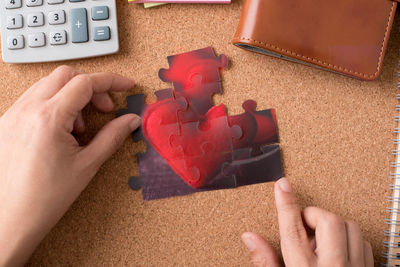 Cropped hands arranging heart shaped jigsaw pieces at table
