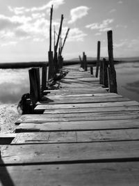 Wooden pier leading towards sea against sky