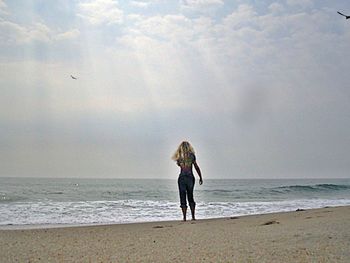 Woman standing on beach against sea