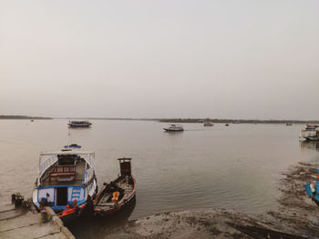 Boats moored in sea against clear sky