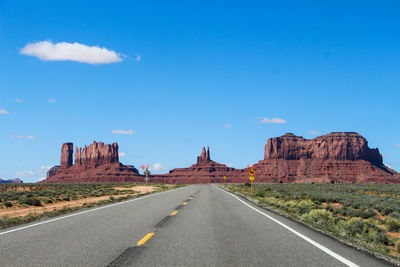 Road leading towards rock formation against sky