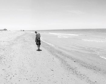 Full length of shirtless man standing at beach against sky during sunny day