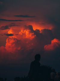 Rear view of silhouette people against dramatic sky during sunset