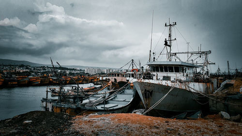 Ships moored at harbor against sky